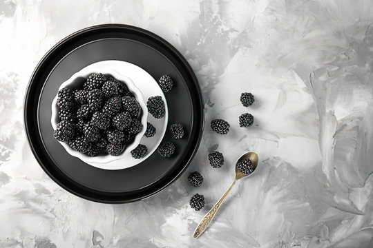 Bowl with delicious ripe blackberries on grey background