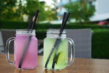 Glass mason jars with fresh drinks on table outdoors