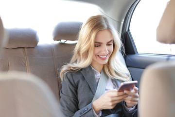 Young businesswoman with mobile phone in car
