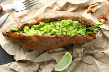 Baked sweet potato stuffed with guacamole on table