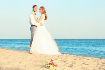 Fototapeta na wymiar Beautiful bouquet and happy wedding couple on sea beach