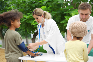 Volunteer doctor measuring blood pressure of poor African child outdoors