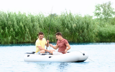 Two men fishing from inflatable boat on river