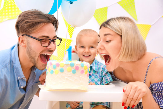 Baby boy with parents and birthday cake at home