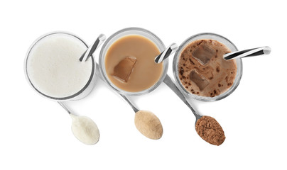 Glasses with different protein shakes and powders in spoons on white background