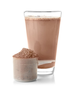 Glass with protein shake and powder in scoop on white background