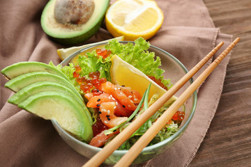 Bowl with delicious salmon salad on table
