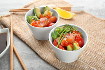 Bowls with delicious salmon salad on table