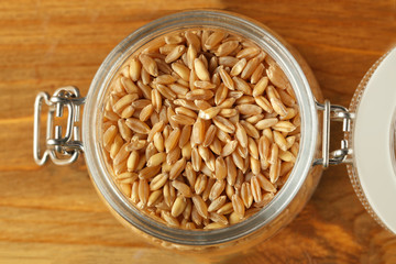 Jar of wheat grass seeds for sprouting on table