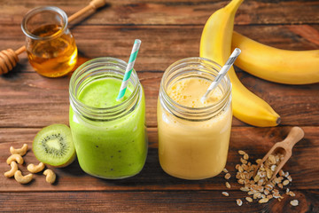 Jars with tasty protein shakes on wooden table