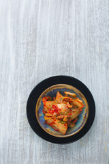 Kimchi in a small ceramic dish - traditional Korean fermented appetizer food. wooden background, copy space 