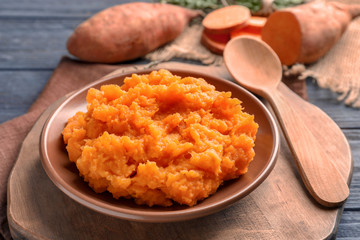 Plate with mashed sweet potato on wooden board