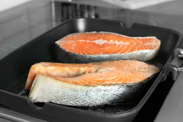Grill pan with delicious salmon steaks on stove in kitchen