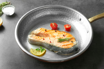 Frying pan with delicious salmon steak on table