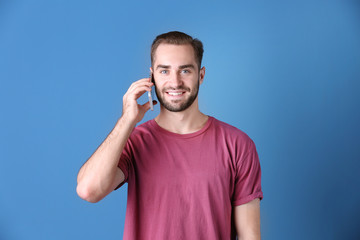 Attractive young man with smartphone on color background