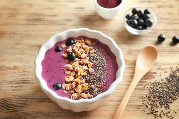 Bowl with acai smoothie, muesli and chia seeds on wooden background