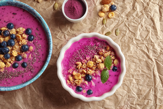 Bowls with acai smoothie, berries and muesli on paper