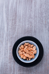 Spicy peanuts in a small dish. Rustic wooden background. Copy space. 