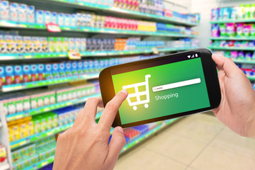 Hand holding mobile phone at supermarket checkout background, e coupon concept