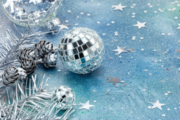 silver balls and fir-tree branches with star shaped confetti on festive blue background