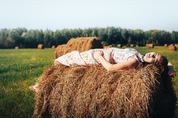 Girl in an autumn field with hay stack