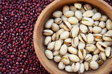 pistachios in wooden bowl on red bean background