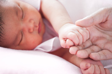 Tiny newborn baby hand holding mother finger with love in soft color tone