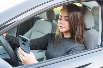 Fototapeta na wymiar Teen Girl Driving Car While Texting