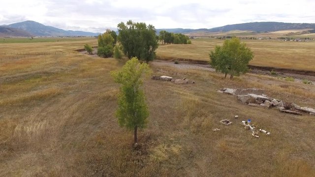 Flying through trees rising up and over past dry riverbed to view the landscape in Wyoming.