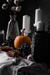 Autumn decor of a table with a pumpkin, white candles, fruits and Viennese wafers