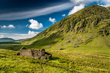 The ruins of an old isolated house or farm in the green hills of Kerry, Ireland