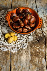 Roasted chestnuts in a bowl on old wooden table. top view 