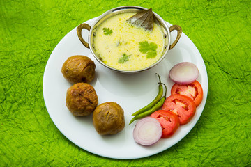 Tradtional Rajsthani food Kadi Bati or Dal Bati served with salads - tomato, onion and green chilli
