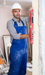 Professional constructor in helmet is measuring doorway