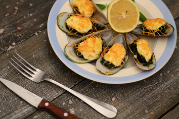 Mussels baked with spinach and Parmesan cheese with lemon and mint on a plate