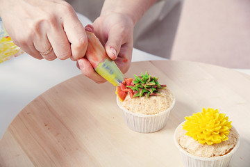 confectioner decorates  cupcake