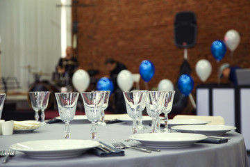 Preparation for a banquet. The tables are covered with a tablecloth. Wine glasses are on the tables in the restaurant.