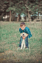 Fototapeta premium Cute handsome boy teen with blue eyes playing outdoor with amazing white pink labrador retriever puppy enjoying summer sunny day vacation weekend with full happyness.Happy smiling kid with best friend
