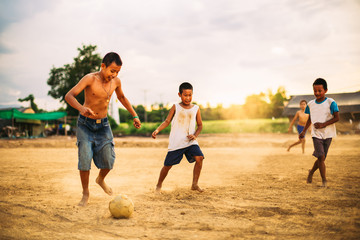 Naklejka premium An action picture of a group of kids playing soccer football for exercise in community rural area.