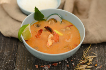 Traditional Thai soup with seafood, mushrooms and coconut milk in a bowl with rice