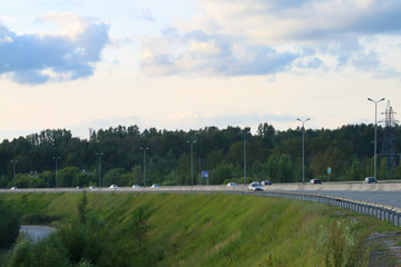 Fototapeta na wymiar Many modern cars move on modern highway at summer evening