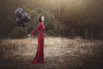 mujer pensativa con globos en el campo