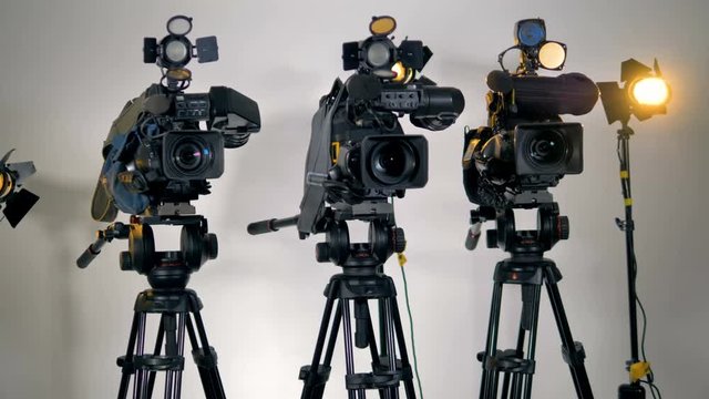 A row of several professional cameras on tripods. 