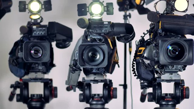A zooming in on three professional video cameras. 