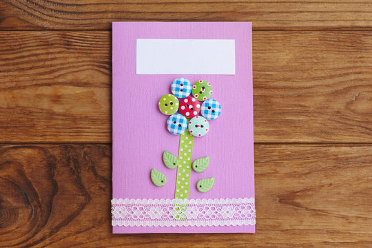 Greeting card isolated on a brown wooden background. Greeting paper card for happy birthday or mother's day or father's day. Birthday invitation. Simple kids craft work with paper. Top view
