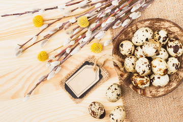 Quail eggs in the bowl and bouquet of dry flowers on the wooden background
