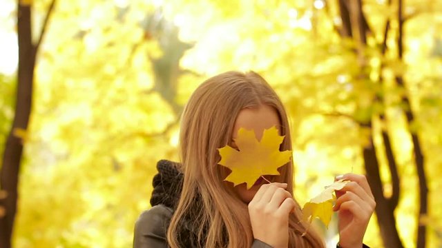 Girl closing and opening her eyes with autumn leaves.