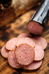 Pile of delicious smoked sausage on a burnt wooden cutting board.