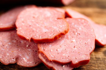 Closeup of sliced delicious smoked sausages on burnt wooden cutting board.