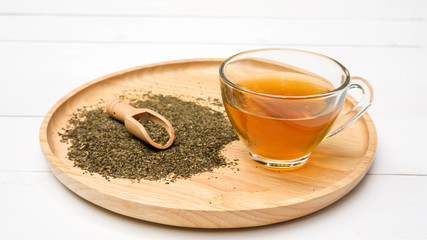 A cup of tea and a green tea leaf on a table.